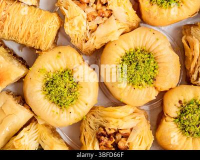 Blick von oben auf verschiedene Baklava mit Nüssen aus nächster Nähe auf weißer Platte Stockfoto