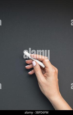 Die schöne junge Frau hand mit Pastell rosa Maniküre holding Stück Kreide auf Tafel Hintergrund. Schule Konzept. Für weibliche Blog soc-Vorlage Stockfoto