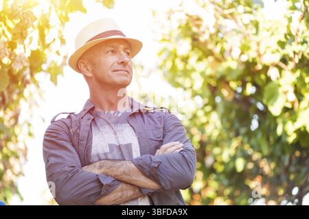 Winzer im Weinberg. Gut aussehender älterer Mann im Stroh Hut und Hemd posieren. Traditionelle Familie Winzer. Ernte im Weingut indust Stockfoto