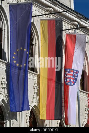 Weimar, Deutschland. 30. Mai 2025. Flaggen für Europa, Deutschland und Thüringen fliegen vor dem historischen Rathaus von Weimar auf dem Marktplatz. Das permanente Fahnenfliegen auf öffentlichen Gebäuden wird zu einem Thema. Immer mehr Kreise in Thüringen diskutieren darüber, ob vor Schulen und Verwaltungsgebäuden ständig Fahnen fliegen sollen. Quelle: Martin Schutt/dpa/Alamy Live News Stockfoto