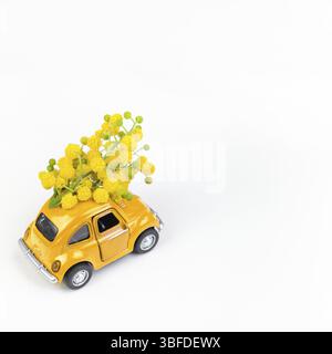 Moskau, Russland - 23. Februar, 8. März 2019: Internationaler Tag der Frau Karte mit Spielzeug Modell retro Auto Lieferung Blumenstrauß von Mimosa Blumen auf Weiß zurück Stockfoto