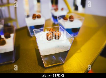 Modernes Dessert in mehreren Schichten in Plastikbecher mit knusprigem Schokoladenbelag Stockfoto