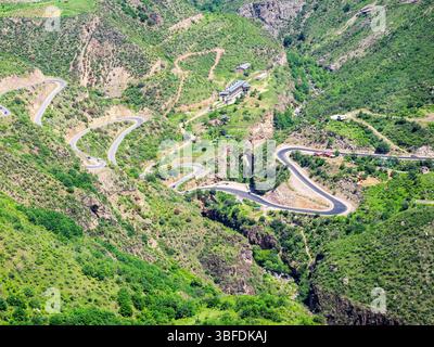 Über dem Blick auf die Serpentinenstraße in der Bergschlucht des Vorotan River mit Teufelsbrücke, zwischen den Dörfern Tatev und Halidzor von der Seilbahn Wings of Tatev Stockfoto