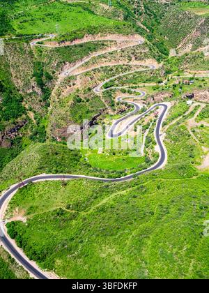 Über dem Blick auf die Teufelsbrücke auf der Serpentinenstraße in der Bergschlucht des Vorotan River zwischen den Dörfern Tatev und Halidzor von der Seilbahn Wings of Tatev o Stockfoto