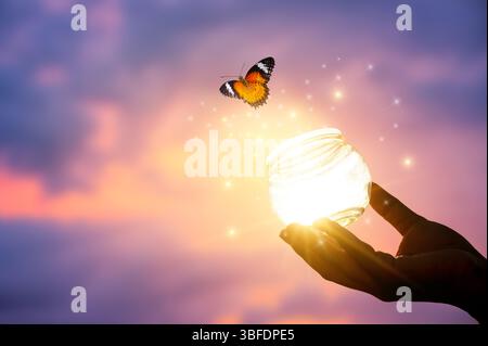 Fliegende Schmetterlinge und Hände auf abstraktem sonnigen natürlichen Hintergrund. Ende des Sommers Konzept. Freiheit. Begegnung mit Mensch und Natur. Harmonie, friedliche Atmosphäre Stockfoto