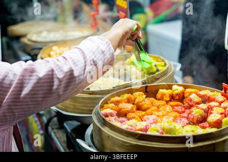 Ein Blick auf eine Dim Sum im Bambusdampfer. Verkäufer, der seine Kunden auf einem Markt bedient. Stockfoto