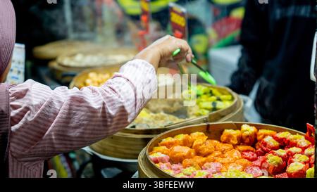 Ein Blick auf eine Dim Sum im Bambusdampfer. Verkäufer, der seine Kunden auf einem Markt bedient. Stockfoto