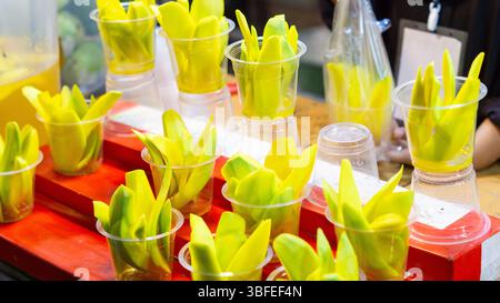 Eingelegte Mango in Plastikbechern. Ein typischer indonesischer Snack aus geschnittener ​​young-Mango, eingeweicht in einer Lösung aus Essig, Salz, Zucker und scharfem Gewürz Stockfoto