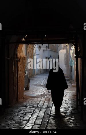 Muslimische Frau, die in einer dunklen Straße läuft, Tunesien, Afrika Stockfoto