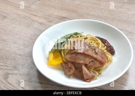 Gebratene Spaghetti mit knusprigem Schweinebeck und trockener Chili mit Paprika auf dem Teller Stockfoto