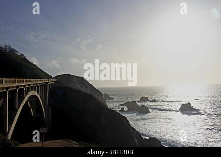 Dramatische Aussicht auf eine Küstenbrücke mit felsigen Klippen und den Pazifischen Ozean bei Sonnenuntergang in der Nähe von Big Sur, Kalifornien, USA. Stockfoto