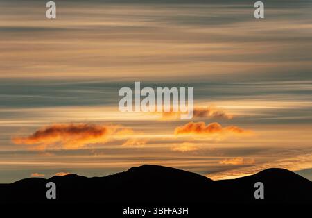 Ein herrlicher Sonnenuntergang über den Silhouetten der Berge. Herrlicher Sonnenuntergang mit üppigen, bunten Goldwolken. Stockfoto