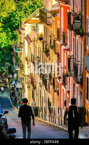 Farbenfrohe Fassaden und schmiedeeiserne Balkone in einer steilen Straße des Lissabonner Stadtteils Bairro Alto. Sonniger Nachmittag in Portugals Hauptstadt. Stockfoto