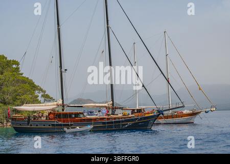 Die Schönheit einer mediterranen Bucht, in der klassische Segelyachten aus Holz eine friedliche Ruhe in unberührter Natur finden Stockfoto