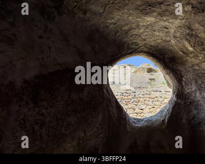 Blick aus dem Inneren der Höhle durch eine runde Öffnung in Uplistsikhe, alte Höhlenstadt in Georgia, historische archäologische Stätte. Keine Personen. Stockfoto