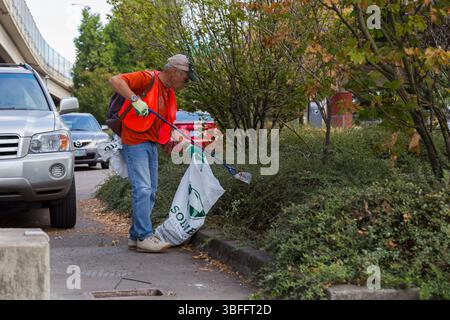 Portland, Oregon – 17. August 2017: Ein Freiwilliger sammelt Müll am Straßenrand mit einem Müllgreifer und einem Müllbeutel. Stockfoto