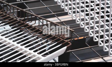 Eine Nahaufnahme eines weißen Grills mit schwarzen Löchern. Der Grill besteht aus Metall und hat ein Gittermuster. Das Bild wirkt minimalistisch, mit dem Stockfoto