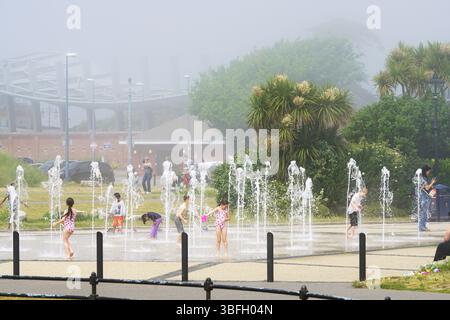 Kinder, die an einem nebeligen Sommertag im Fountain Splash Pad spielen. Portsmouth, Großbritannien Stockfoto