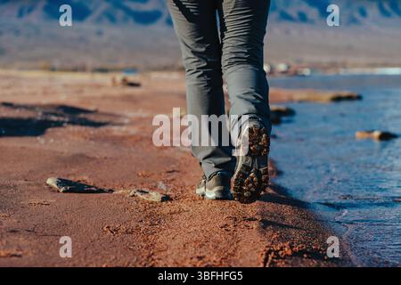 Frau läuft entlang des Sandufers des Sees, Schuhe aus nächster Nähe Stockfoto