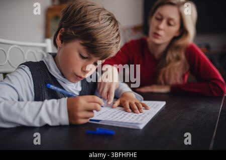 Junge Schüler macht seine Hausaufgaben zu Hause mit seiner Mutter Stockfoto