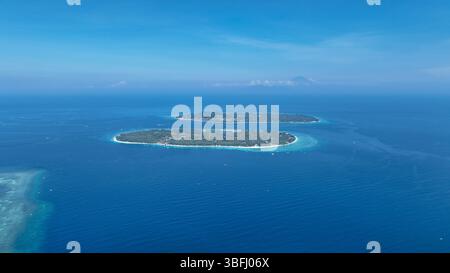 Dieses Bild, das über dem türkisfarbenen Meer schwingt, fängt das bezaubernde Duo Gili Meno und Trawangan mit dem Berg Gunung Agung im Hintergrund ein. Das Endl Stockfoto
