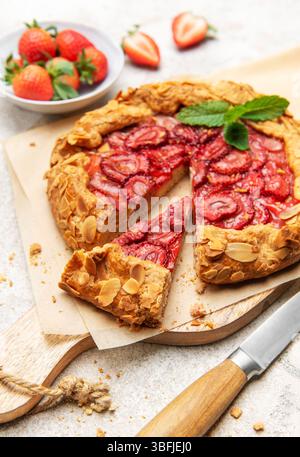 Frisch gebackene Erdbeergalette, dekoriert mit Mandelflocken und Minzblättern, mit einem Ausschnitt Stockfoto