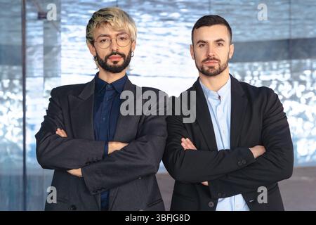 Zwei selbstbewusste Geschäftsleute stehen mit überkreuzten Armen und ernsten vor der Kamera Stockfoto