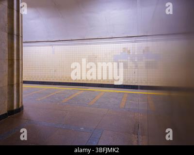 Leerer Bahnsteig einer unterirdischen U-Bahn-Station mit gelben Markierungen auf dem Boden und gekachelten Wänden Stockfoto