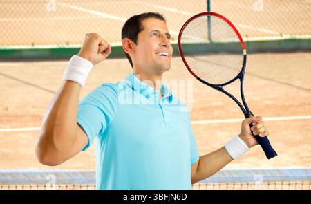 Porträt eines jungen Tennisspielers, der auf einem Tonplatz den Sieg feiert Stockfoto