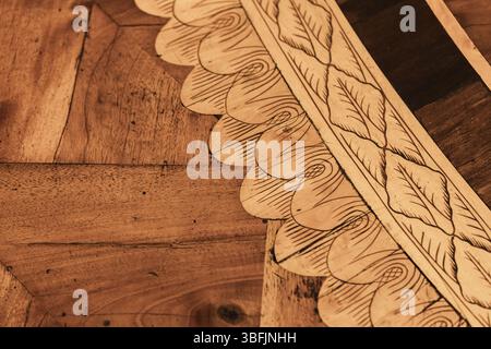 Detaillierte Holzparkettpaneele mit aufwändigen Schnitzereien aus Blättern und Wirbeln, die Handwerkskunst und natürliche Ästhetik zum Ausdruck bringen. Perfekte Darstellung o Stockfoto