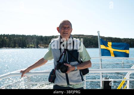 Rentner, der Fotos auf einem Boot macht, während er in Schweden Besichtigungen macht Stockfoto
