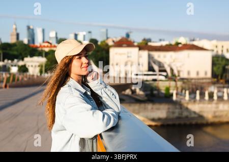 Junge Frau entspannte sich und genießt den Blick auf die Stadt im Sonnenlicht Stockfoto