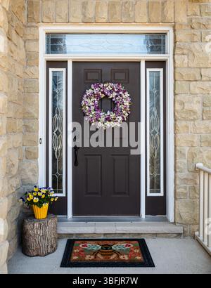 Front door of home decorated for spring with wreath and flowers. Stockfoto