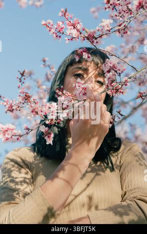 Eine junge Frau, die einen Baum mit Blumen hält Stockfoto