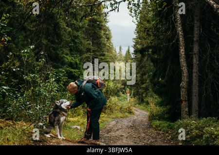 Frau verbindet sich mit Hund auf schlammigem Waldweg in Nordschweden Stockfoto
