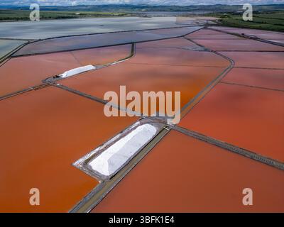 Aus der Vogelperspektive der farbenfrohen Salinen in der Nähe von Burgas, Bulgarien. Leuchtend rote und orangene Verdunstungsteiche stehen im Kontrast zu weißen Salzhaufen und türkisfarbenem Meer Stockfoto
