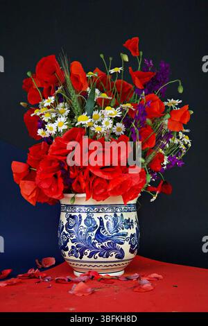 Die rustikale rumänische Töpfervase ist voller Wildblumen und lebendiger Mohnblumen, die Tradition und Natur in einer farbenfrohen, herzlichen Ausstellung vereint Stockfoto