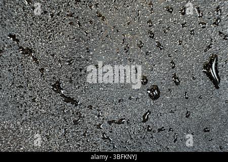 Wassertropfen auf einer gusseisernen Makrooberfläche. Gusseiserne Kochgeschirr Pflege, rostbeständig, abstraktes Muster. Stockfoto