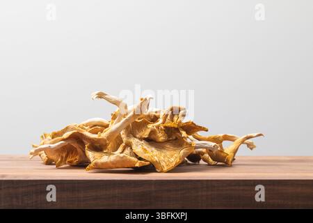 Haufen getrockneter Austernpilze auf hölzernem Schneidebrett in hellem Studio-Licht, mit natürlicher Textur und Bio-Zutaten Stockfoto