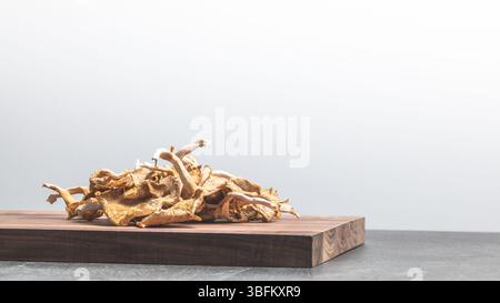 Studio-Nahaufnahme mit getrockneten Austernpilzen auf Holzbrett, helles Licht hebt Textur und Bio-Food-Styling hervor Stockfoto