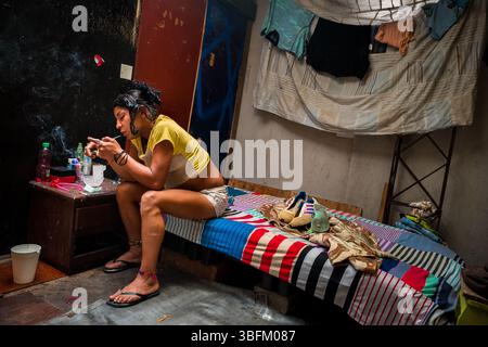 Ein kolumbianischer Drogenkonsument raucht Basuco – eine unraffinierte, schmutzige Kokainpaste –, während er in einem Raum sitzt, der an Drogenabhängige in Medellín, Kolumbien, vermietet wurde. Stockfoto