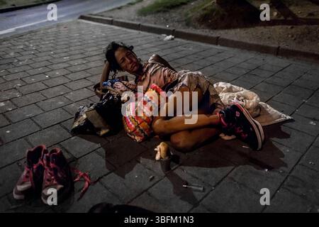 Eine kolumbianische Drogenkonsumentin schläft auf dem Boden, neben ihren Turnschuhen und Gegenständen, im Zentrum von Medellín, Kolumbien. Stockfoto