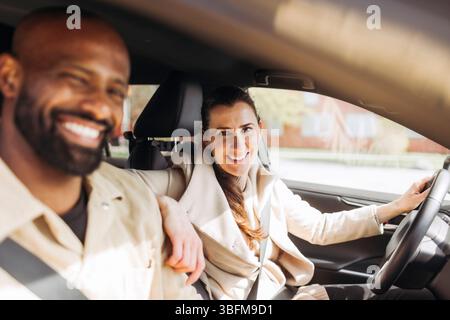 Porträt einer lächelnden Frau, die mit der Hand auf der Schulter des Mannes im Auto sitzt Stockfoto
