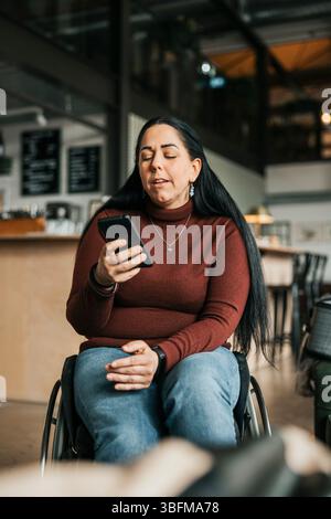 Geschäftsfrau mit Behinderung mit Smartphone im Büro Stockfoto