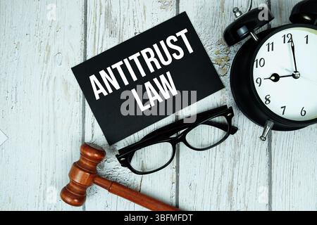 Kartellrecht Textnachricht auf Papierkarte mit Holzgabel und Wecker auf hölzernem Hintergrund Stockfoto