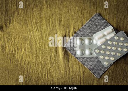 Flache Zusammensetzung mit verschiedenen Pillen und Kapseln in Blisterpackungen auf strukturiertem Gewebe. Sauberer, minimalistischer Pharma- und Wellness-Service Stockfoto