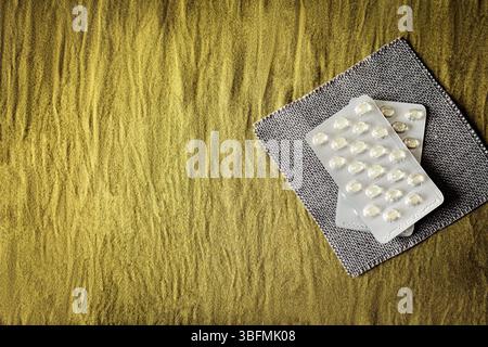 Flache Zusammensetzung mit verschiedenen Pillen und Kapseln in Blisterpackungen auf strukturiertem Gewebe. Sauberer, minimalistischer Pharma- und Wellness-Service Stockfoto