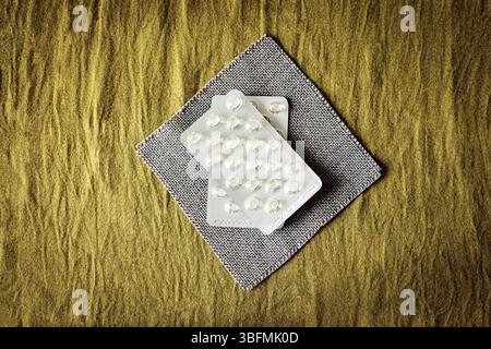 Flache Zusammensetzung mit verschiedenen Pillen und Kapseln in Blisterpackungen auf strukturiertem Gewebe. Sauberer, minimalistischer Pharma- und Wellness-Service Stockfoto
