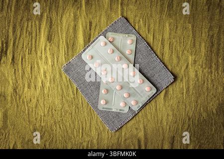 Flache Zusammensetzung mit verschiedenen Pillen und Kapseln in Blisterpackungen auf strukturiertem Gewebe. Sauberer, minimalistischer Pharma- und Wellness-Service Stockfoto