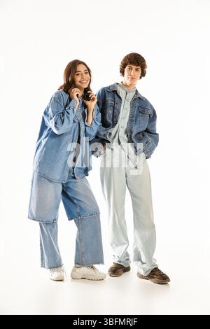Liebevolles Paar in stilvollem Denim, lächelnd und in einem hellen Raum zusammen mit anderen genießt. Stockfoto